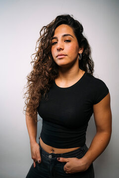 Young woman with curly hair looking at camera expressing confidence