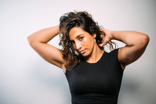 Confident young adult woman posing with curly hair
