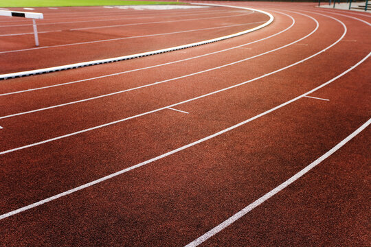 Empty red running track with white marking and a hurdle