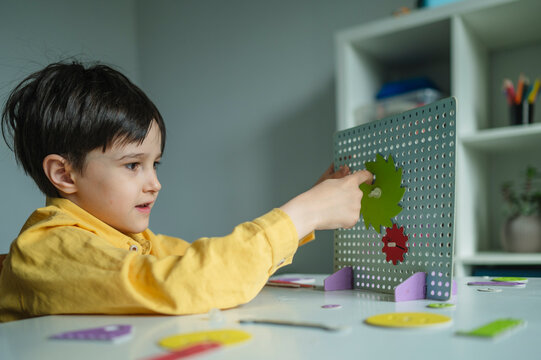 Student experimenting with mechanical gear constructor toy indoors