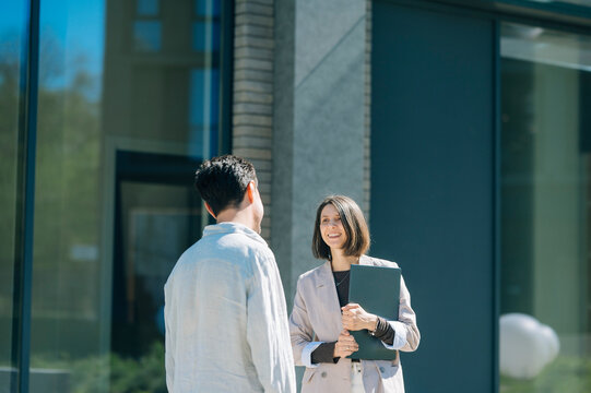 Colleagues talking together outside a modern city office building