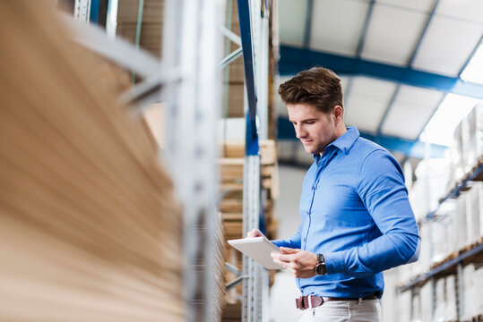 Young man working in warehouse, using digital tablet