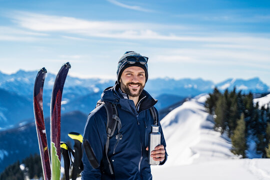 Germany, Bavaria, Brauneck, portrait of smiling man on a ski tour in winter in the mountains having a break