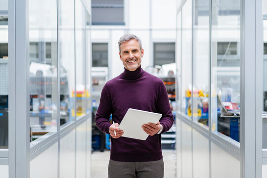 Portrait of smiling businessman holding digital tablet in factory