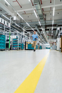 Engineer with tablet walking in organized modern production hall
