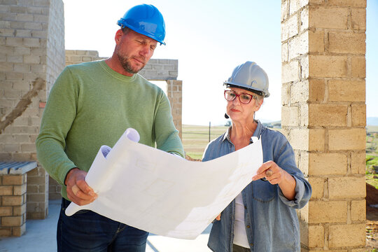Architect and builder discussing building plan at construction site