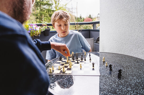 Father and son playing chess outdoors focusing on strategy