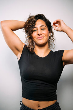 Confident young woman smiling with hands in curly hair