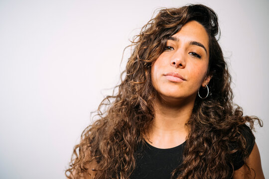 Young adult woman posing with curly hair and hoop earrings