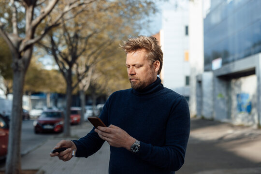 Man locking with key and using smart phone