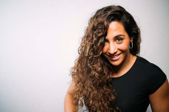 Smiling young adult woman with long curly hair