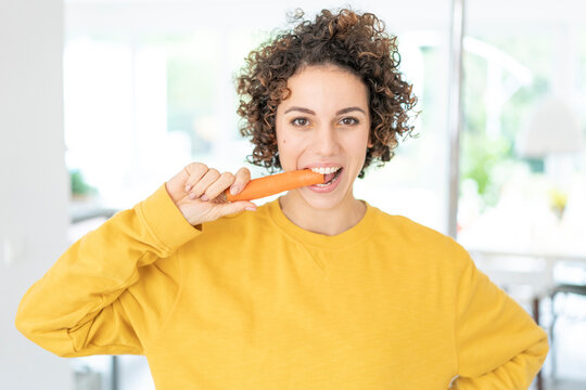 Portrait of woman eating a carrot at home