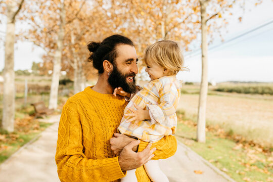 Father carrying his daughter on a morning day in the park in autumn