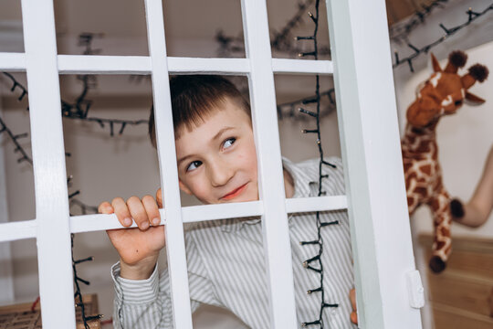 Curious person looking through white wooden gate indoors