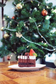 A piece of homemade chocolate mousse cake; decorated with mint leaf and fresh strawberry topped with white cholocate and chocolate sauce on the ceramic plate.