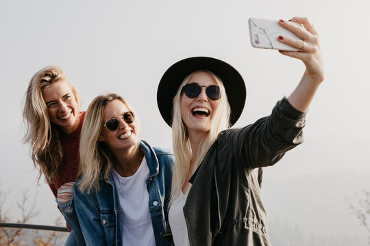 Three happy young women taking a selfie outdoors