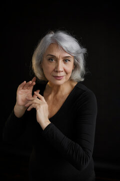 Smiling senior woman with gray hair against black background