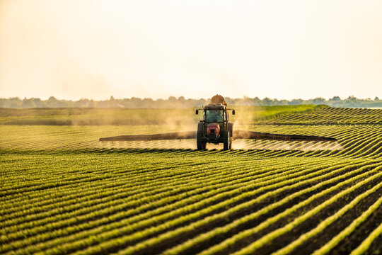 Tractor spraying soybean crops at sunset