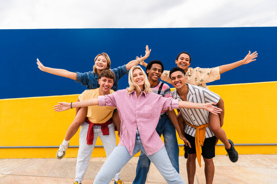 Group of young friends with colorful clothing posing happily in front of wall
