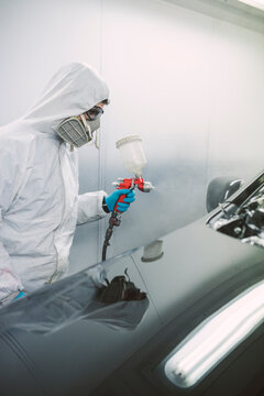 Auto painter painting a car