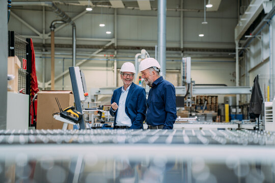 Engineers in hard hats discussing in a factory setting