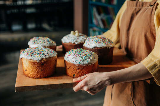 Baker holding wooden board with traditional Easter bread paska