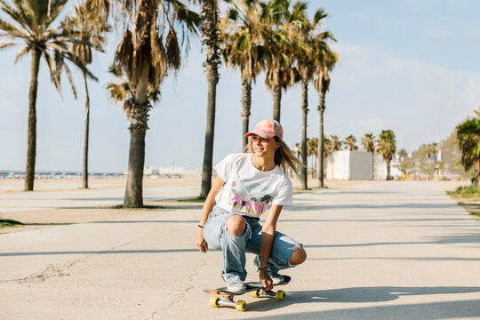 Mid adult woman skating by trees during sunny day at beach