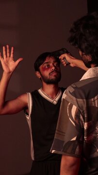 Kidnapped man raising hands as armed captor points handgun in intense fictional hostage scene