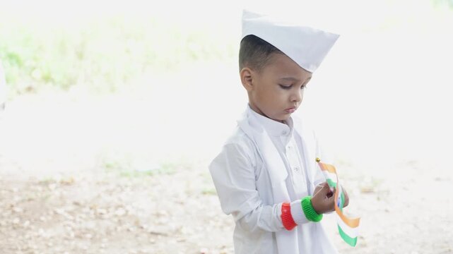 young cute patriot kid in white kurta and gandhi cap carrying indian national flag outdoors