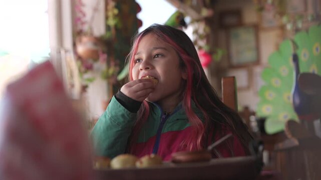 A young girl savors a traditional Argentine empanada in a cozy setting, filled with joy.