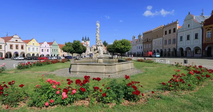 4K right panning motion of the Marian column, A monument statue of the Virgin Mary located prominently on  Hradec Square and gardens with the two main streets of shops and houses of the town Telc