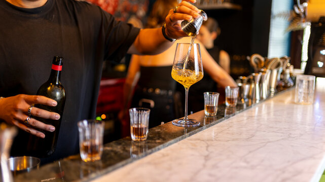 Bartender preparing a premium cocktail with wine and spirits at an elegant bar counter during an evening hospitality service with copy space