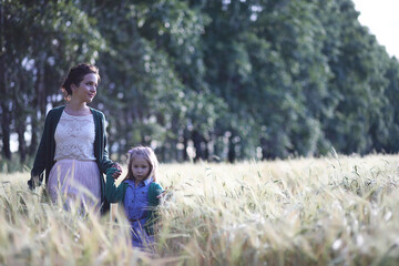 Fototapeta premium A young mother walk in wheat fields