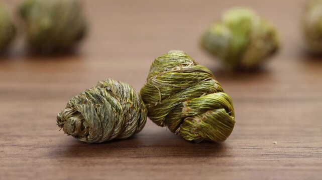 Close-up of dried Dendrobium officinale Fengdou on wooden table, traditional Chinese herbal medicine.