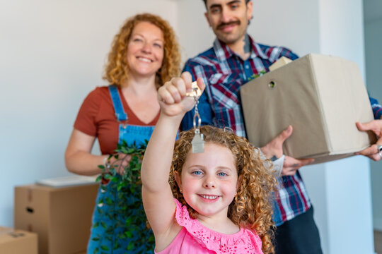 Little girl holding up new house keys with smiling parents