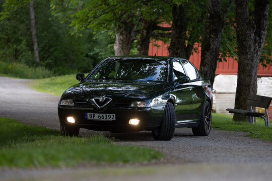 Dark green Alfa Romeo 166 sedan glides through quiet forested lane
