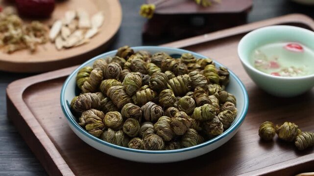 Dried Dendrobium officinale stems rolled into spirals in a ceramic bowl on a wooden tray, Chinese herbal medicine