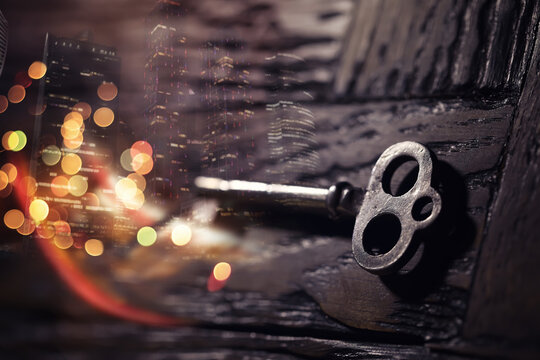 vintage key over old wooden surface with back light. Double exposur night city.