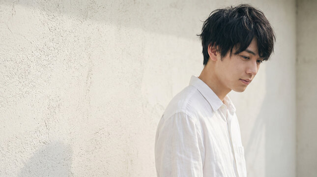 自然光の中でうつむく若い男性の繊細な表情 ｜ 柔らかな陰影