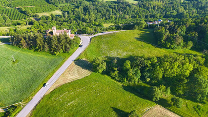 Fototapeta premium Aerial View of Winding Road Through Lush Italian Countryside and Vineyards