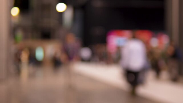 Out of focus shot of diverse people walking through a startup event or business conference hall. Useful for background overlays and tech industry concepts.