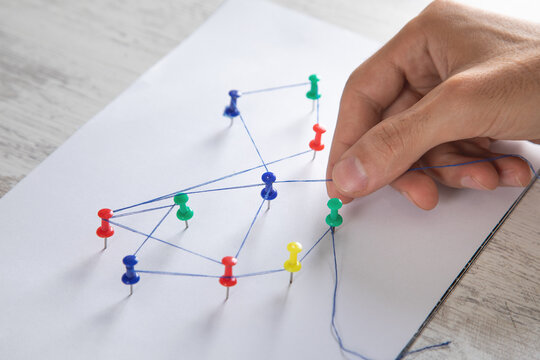 Man showing network connection with a push pins and thread.