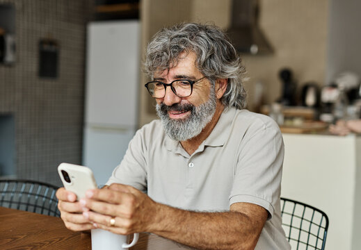Portrait of a cheerful senior elderly man talking on phone at home