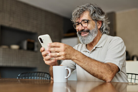 Portrait of a cheerful senior elderly man talking on phone at home