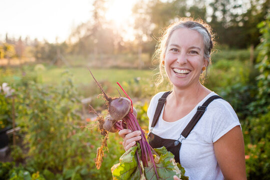 Happy woman holding fresh beets in a sunny garden