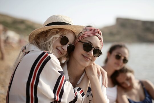 Happy young friends hugging on a sunny beach