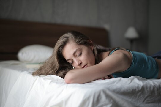 Young woman with long hair sleeping peacefully in bed