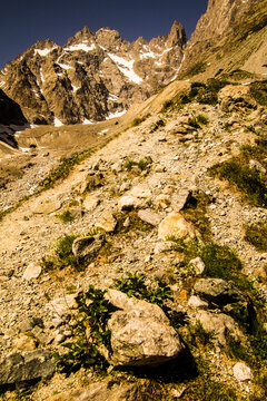 Hikers explore rocky terrain near tall mountains under a clear blue