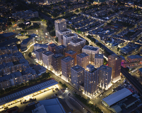 Aerial view of the modern residential development near Wandsworth Town Station with illuminated high-rise buildings and urban streets at night in London, England, United Kingdom.