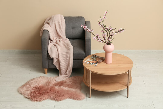 Interior of stylish living room with grey armchair and blooming tree branches on coffee table
